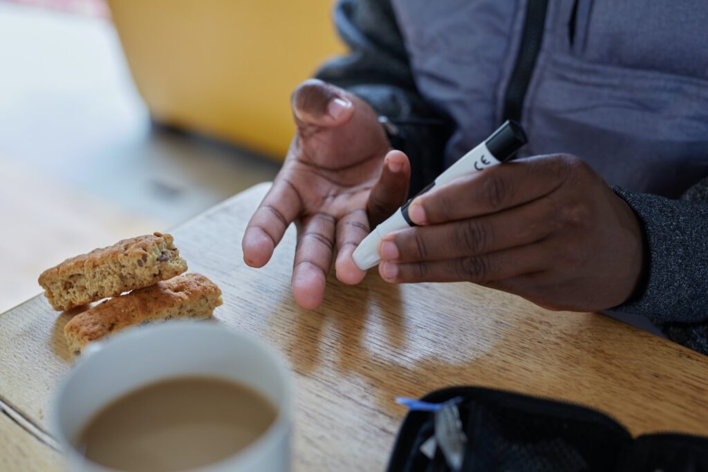 A man testing his glucose level, drinking a coffee.